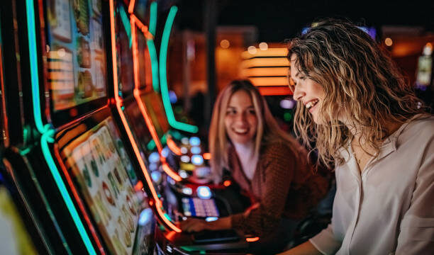 Girl friends gambling in casino on slot machinery